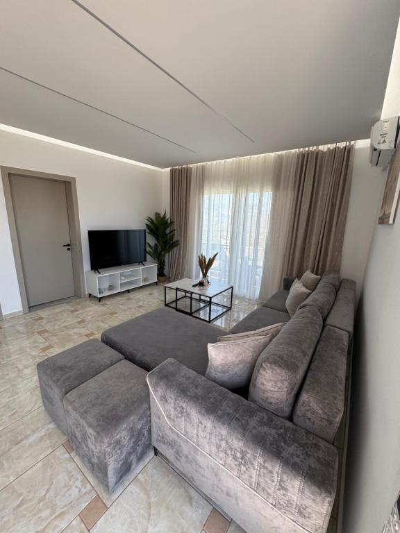 a living room with a large couch and a flat screen tv at Villa Merkaj in Sarandë