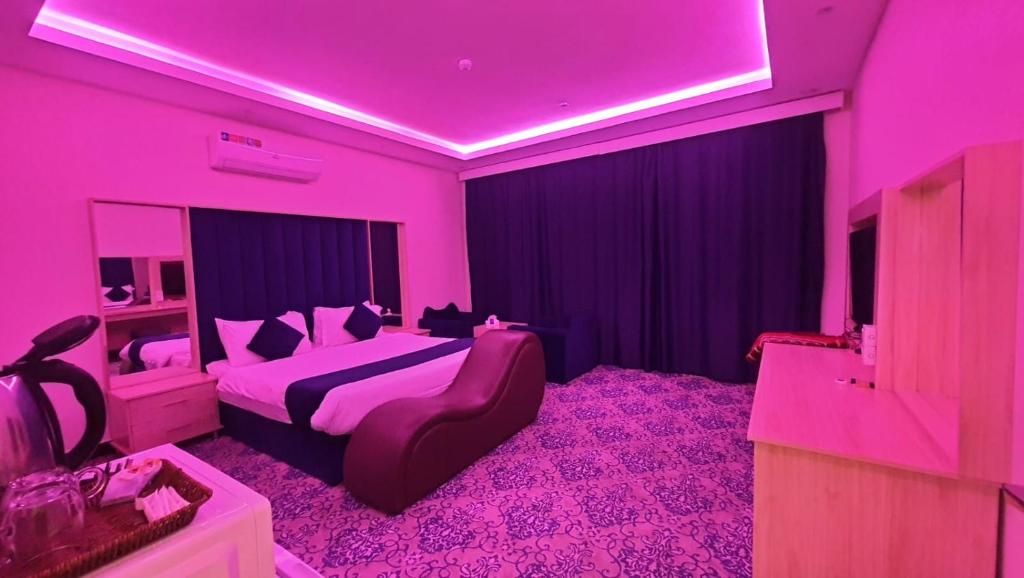 a pink room with a bed and a couch at sala almasa serviced apartments in Abha