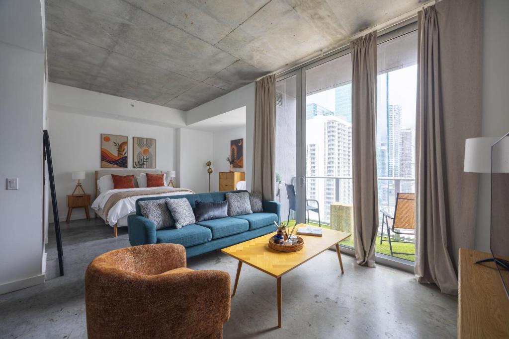a living room with a blue couch and a bed at Chic Studio by Brickell & Miami Beach WD Pool Gym in Miami