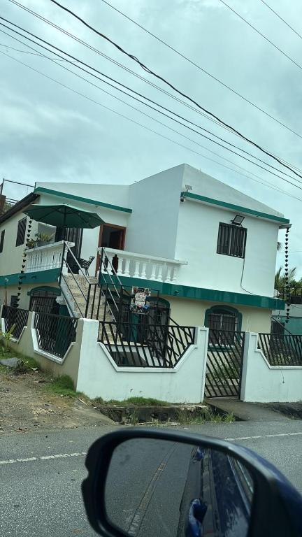 a white house with stairs and a car parked in front of it at Villa Spa Mega Relax in San Francisco de Macorís