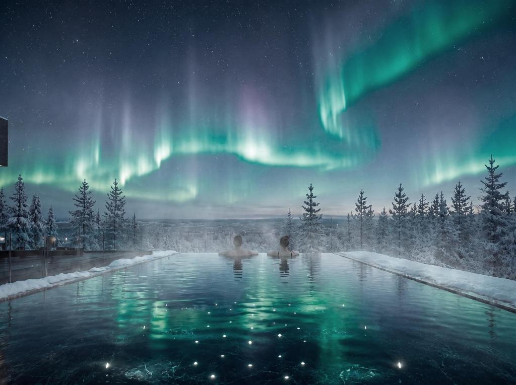 two people in a hot tub under the northern lights at SkyView Igloo Resort & Spa in Rovaniemi