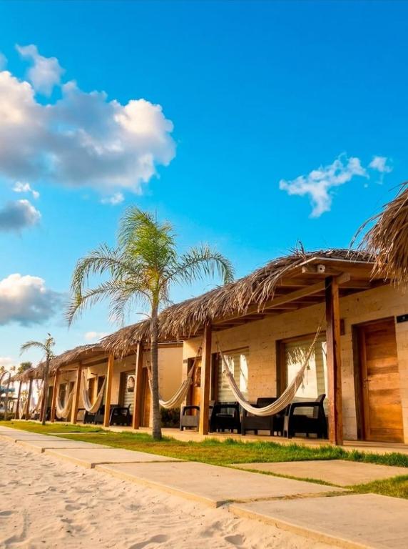 a resort with hammocks and palm trees on the beach at Posada Las Rosas Inn in Quizandal