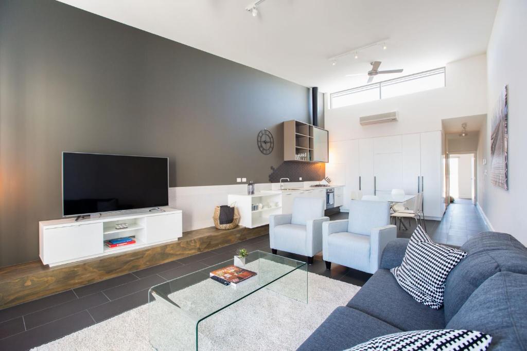 een woonkamer met een blauwe bank en een tv bij Magnificent Apartment + FREE car park near CBD in Adelaide