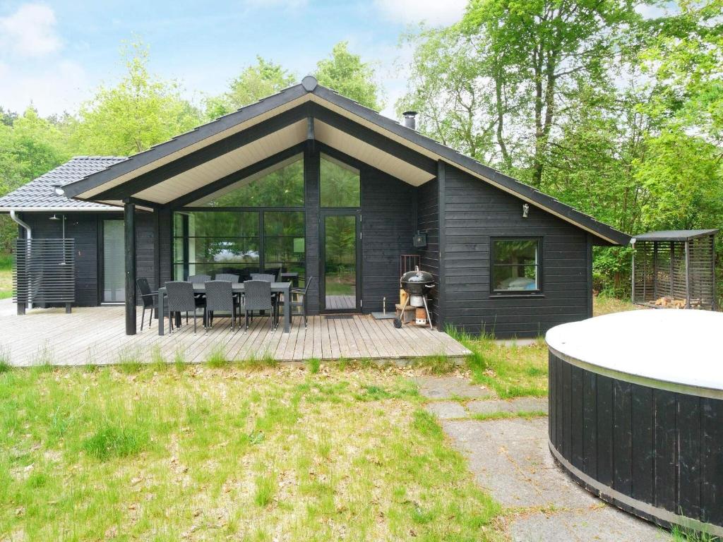 a black house with a deck with a table and chairs at 8 person holiday home in Vig in Vig