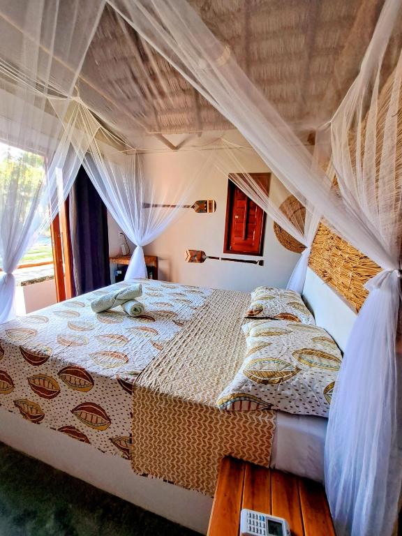 a bedroom with a canopy bed with curtains at Chalé Vera Ar condicionado Pousada 35knots Brasil in Luis Correia
