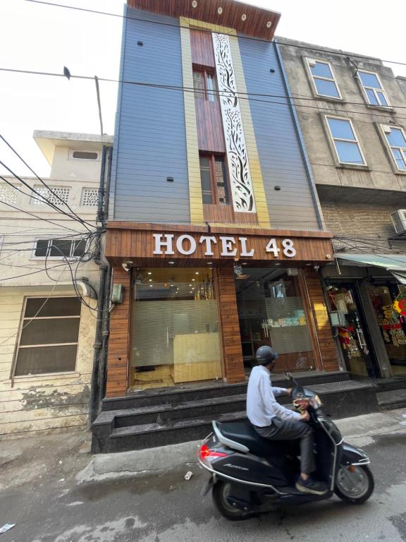 a man riding a scooter in front at Hotel 48 in Amritsar