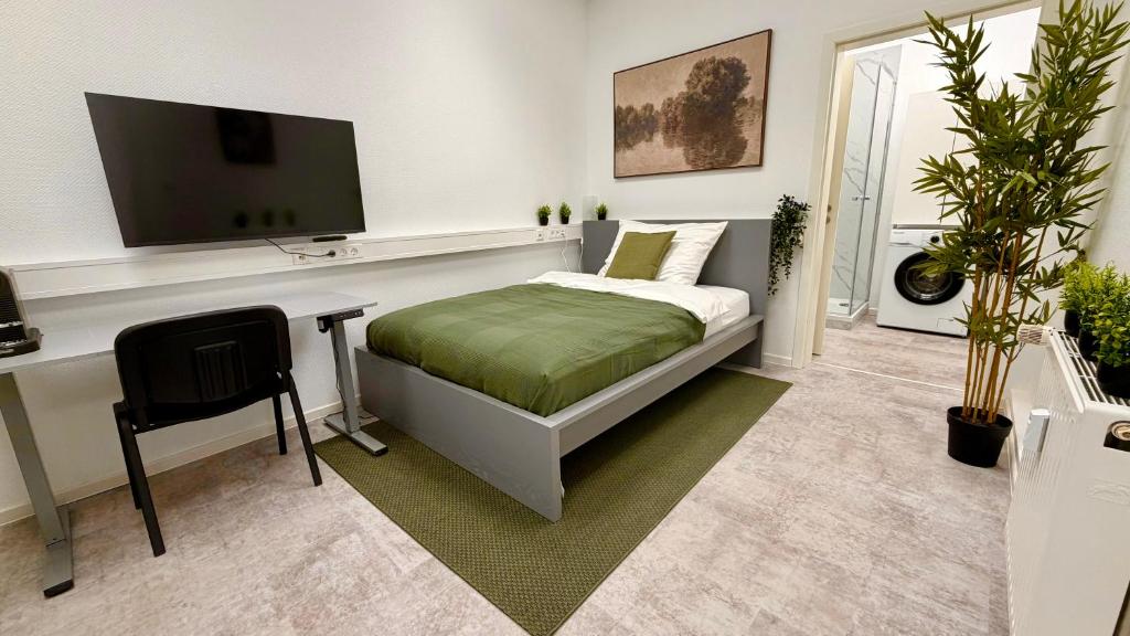 a bedroom with a bed and a desk with a television at MeBa Living Business Suite Mönchengladbach in Mönchengladbach