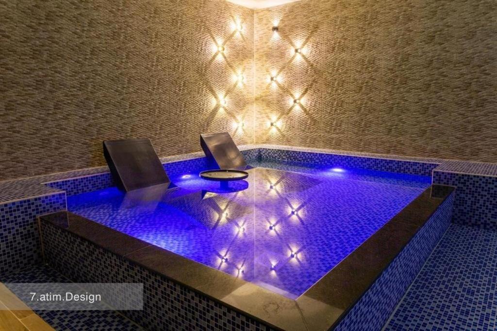 a swimming pool with two chairs in it with blue lights at Chalet A4 Mirbat in Mirbāţ