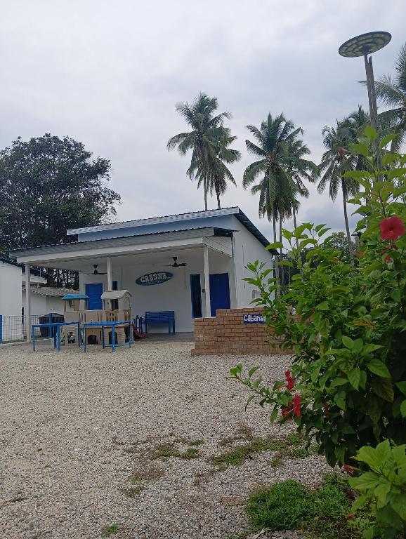 a building with chairs and palm trees in front of it at Cabana Chalet Cherating in Cherating