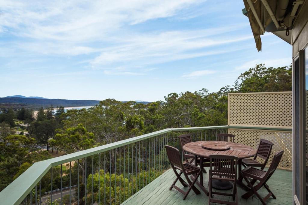 a deck with a table and chairs on a balcony at Holiday on Pacific in Tathra