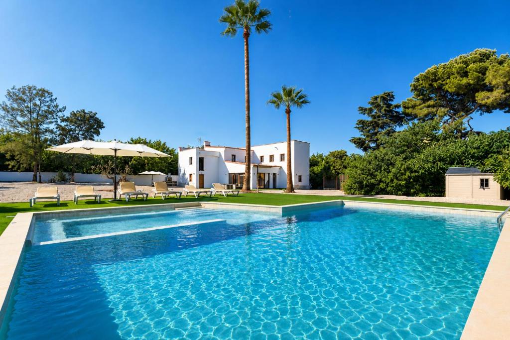 a swimming pool in front of a house with palm trees at Villa MORERA in Vilaseca de Solcina