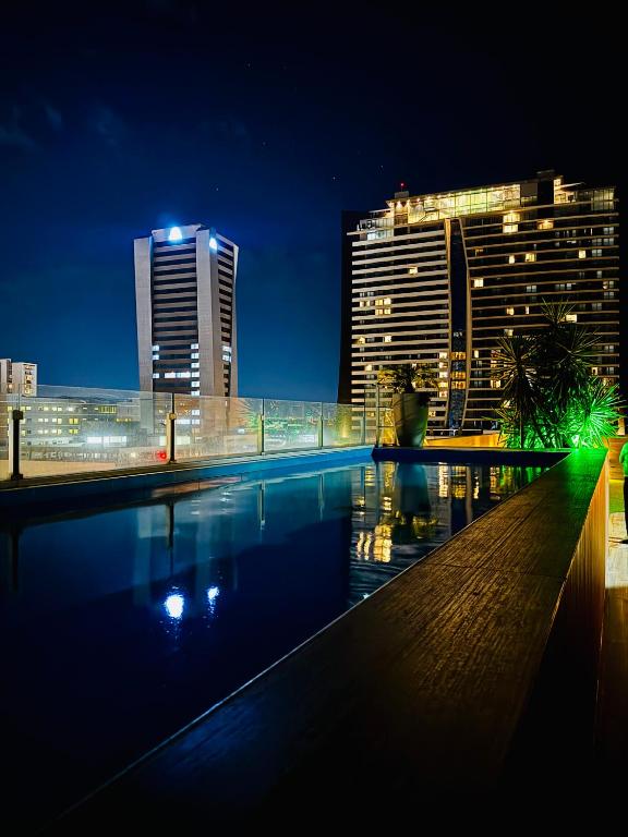 a swimming pool with a city skyline at night at Sirari Palm 102 in Santa Cruz de la Sierra
