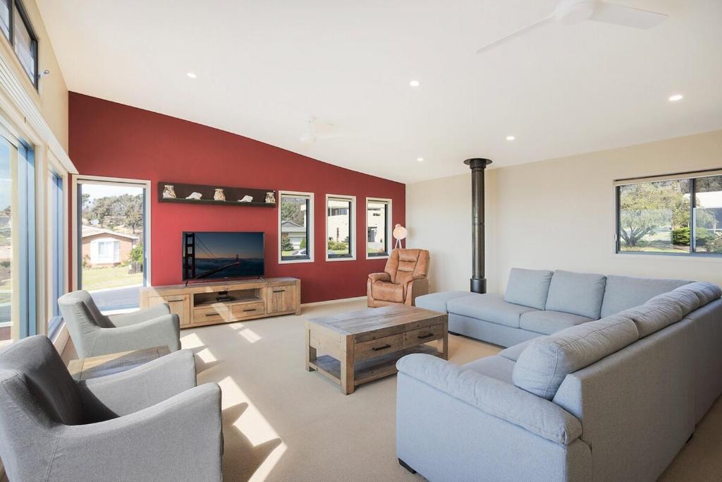 a living room with a couch and chairs and a tv at Fanta Sea in Tathra