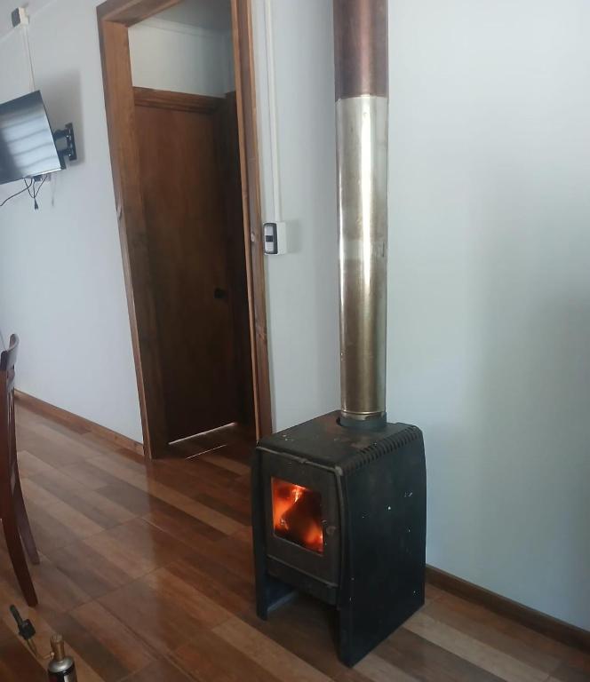 a wood stove in a room with a door at Casa bosque arenal in Pucón