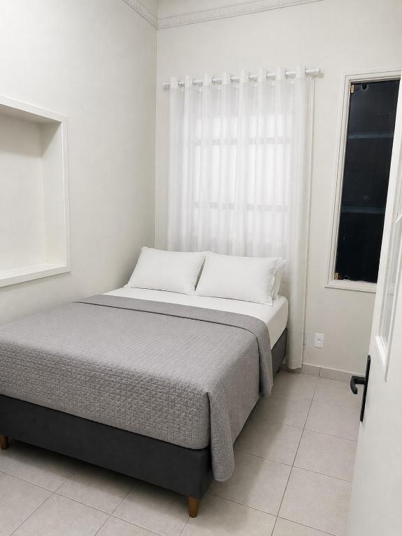 a bed in a white room with a window at ParaHouse in Joinville