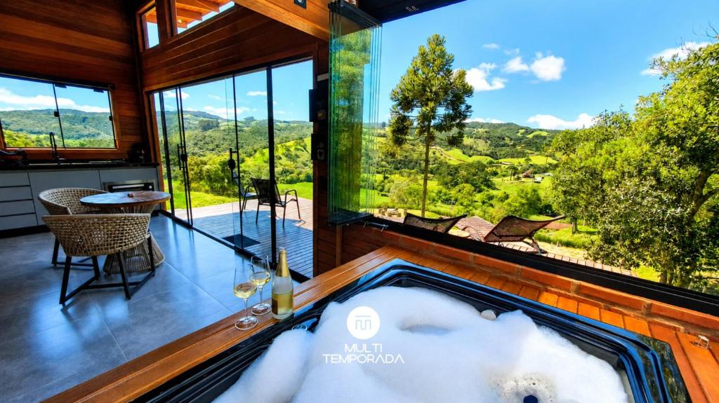 an indoor jacuzzi in a house with a view at Cabana Bad Wolf - Rancho Queimado - SC in Rancho Queimado