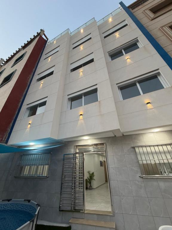 a large white building with a staircase in front of it at Reda Appartements Al Hoceima in Al Hoceïma