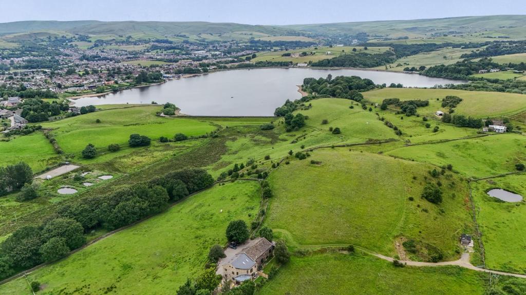 an aerial view of a field with a lake at Bib Knowl Farm in Littleborough