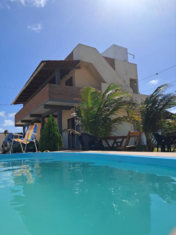 a house with a swimming pool in front of it at POUSADA SOLAR DOS MOREIRAS in Guajiru