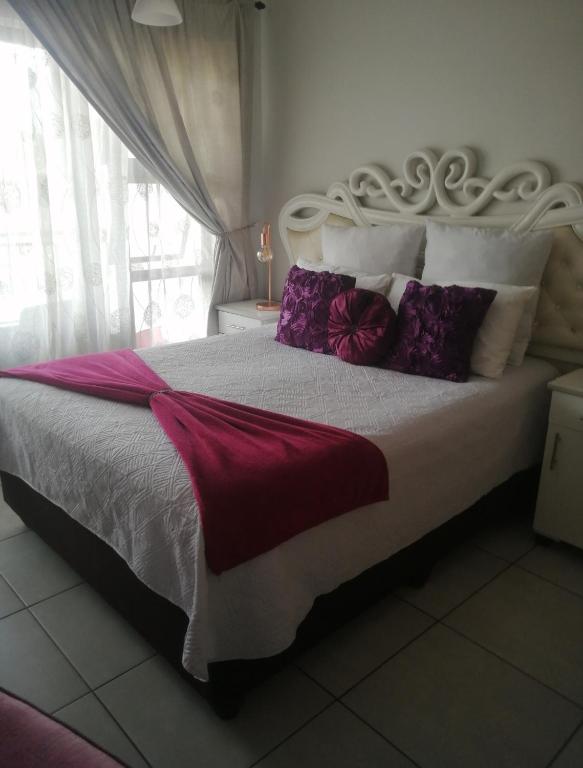 a bedroom with a large bed with purple and white pillows at Iris Bnb on Vaal in Vanderbijlpark