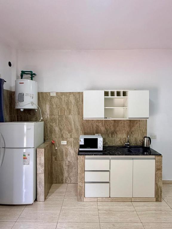 a kitchen with white cabinets and a white refrigerator at Serena Suites in Ezeiza
