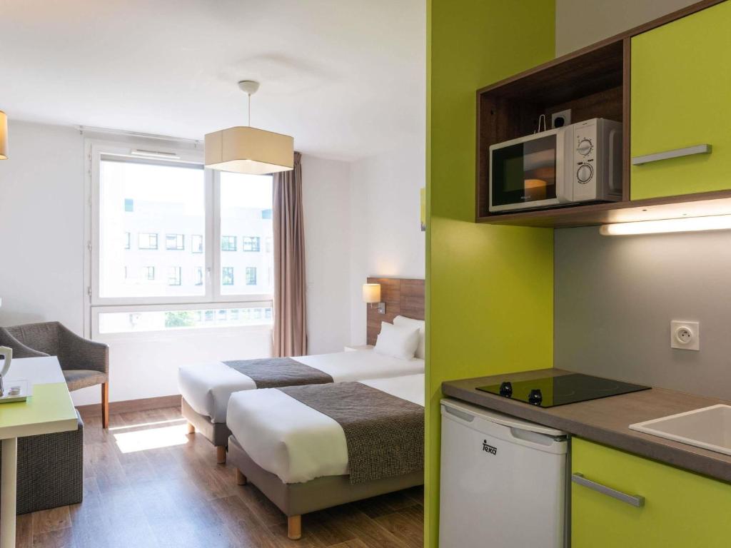 a hotel room with two beds and a kitchen at Adagio Access Grenoble Université in Saint-Martin-dʼHères