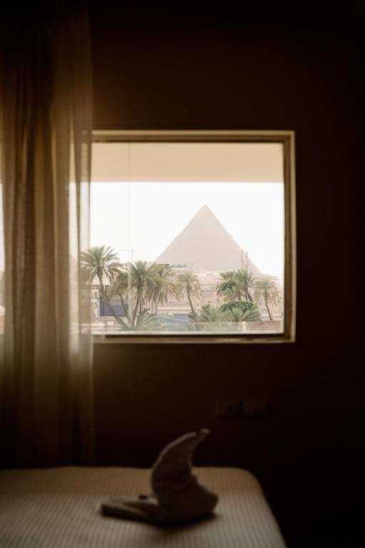 a bird sitting on a bed looking out a window at the pyramid at Irit pyramids inn in Cairo