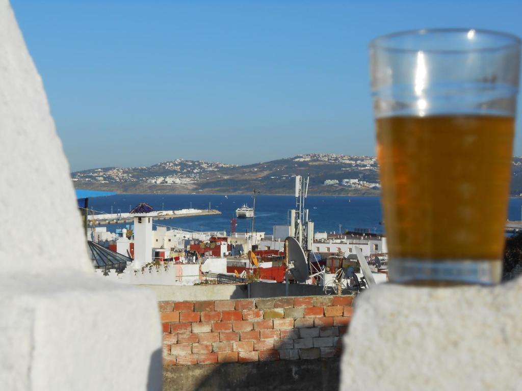 a glass of beer sitting on a ledge with a city at Petit Bijou de Tanger in Tangier