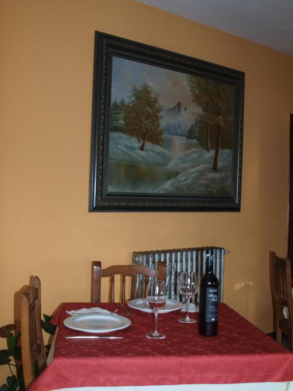 - une table avec un chiffon de table rouge et une bouteille de vin dans l'établissement Pensión HK, à A Angueira de Suso