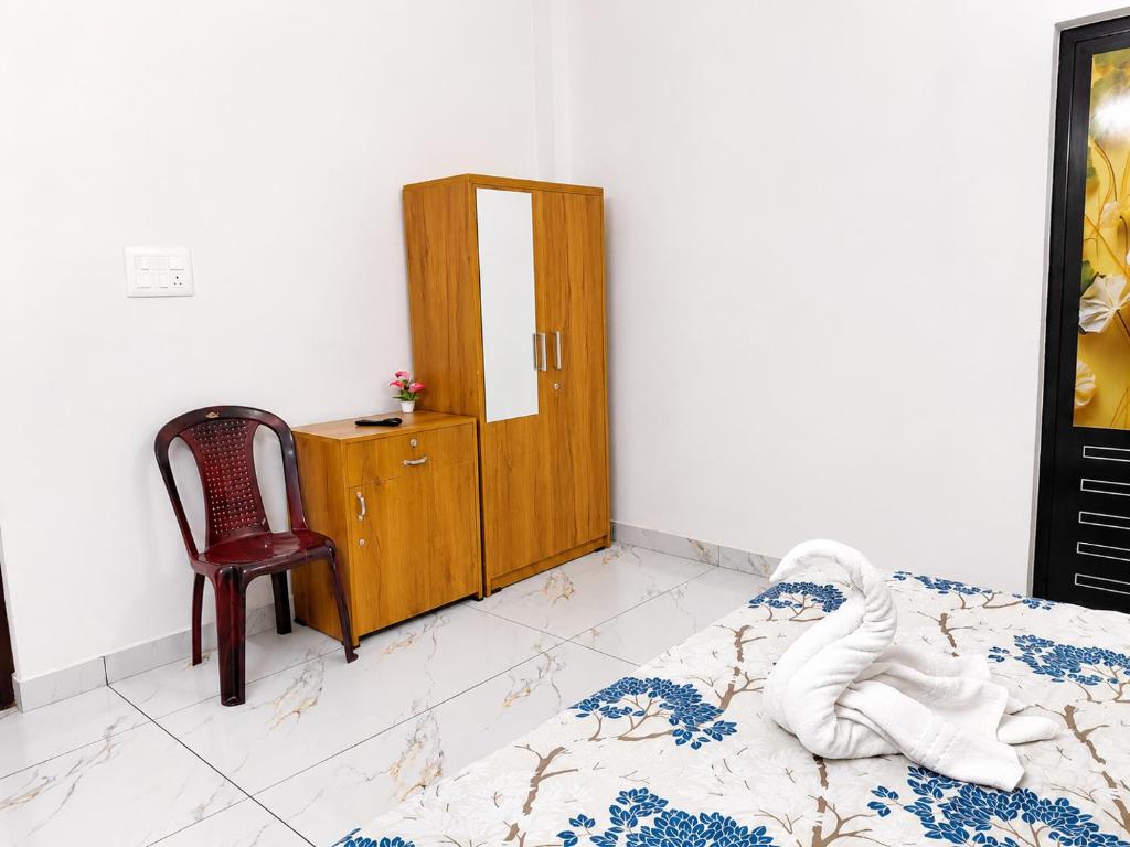a bedroom with a bed and a chair and a cabinet at Zayan Home Stay in Agatti Island