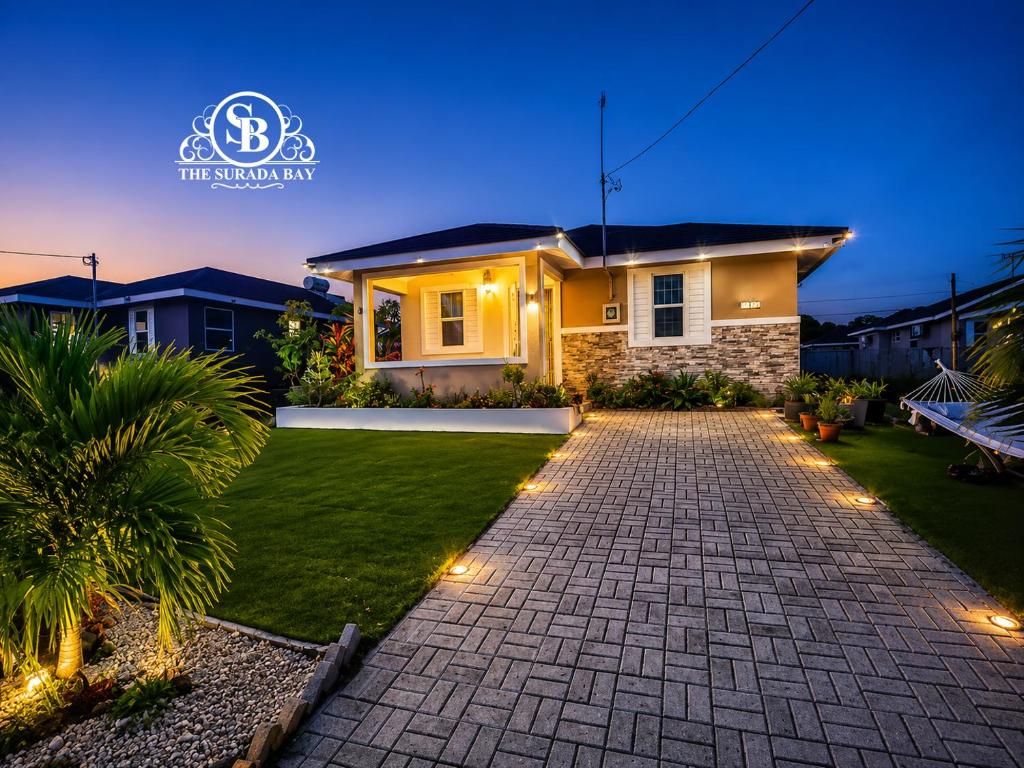 a house with a brick driveway and lights in the yard at The Surada Bay in Old Harbour
