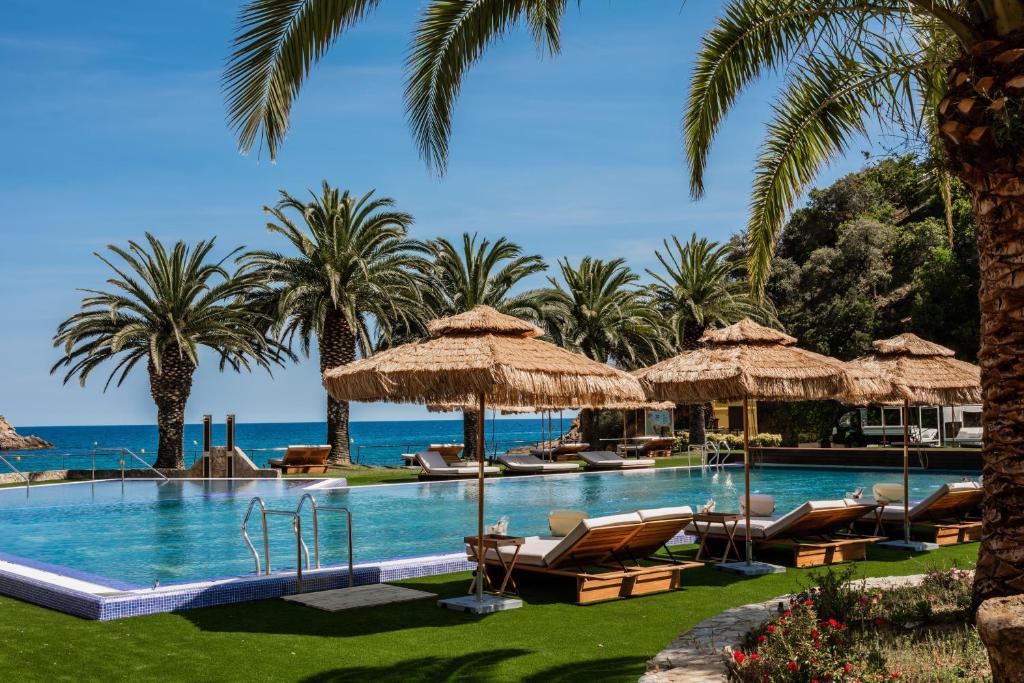 a swimming pool with chaise lounge chairs and palm trees at Zel Costa Brava in Tossa de Mar