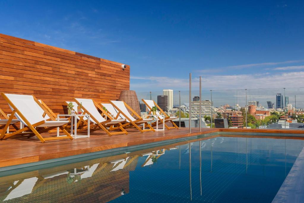 a group of lounge chairs sitting on a deck next to a swimming pool at Meliá Madrid Serrano in Madrid