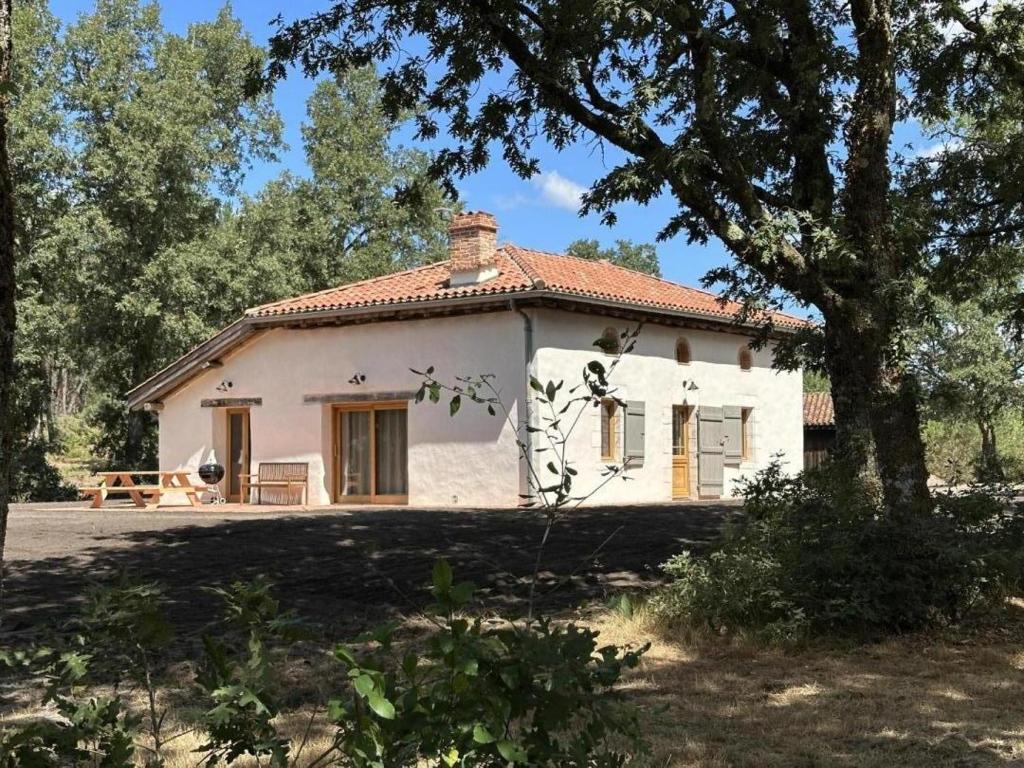 a small white house with a tree in front of it at Le résinier in Commensacq