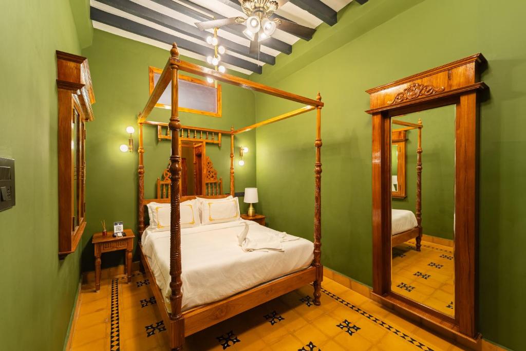 a bedroom with a canopy bed and a mirror at Hotel Palais De Versailles in Pondicherry
