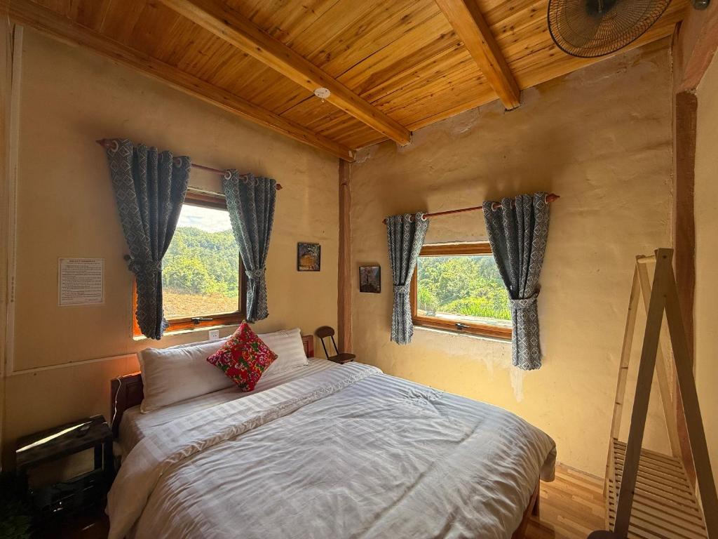 a bedroom with a bed in a room with two windows at Lũng Cú H'Mông Homestay in Loung Co