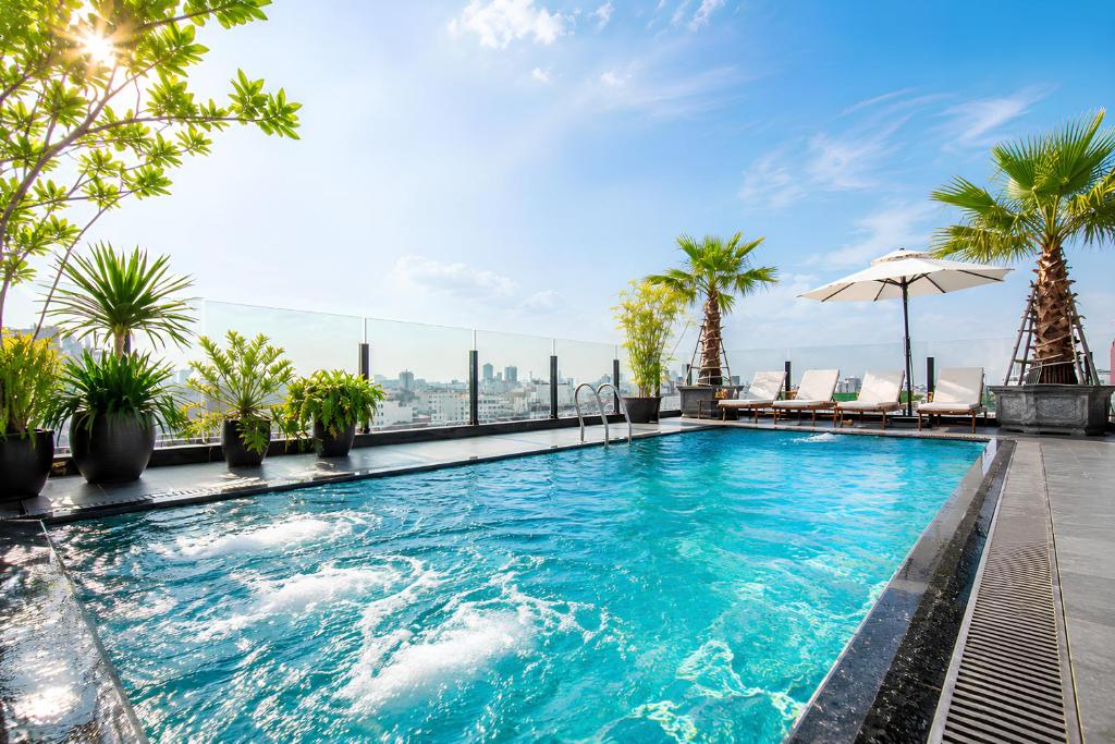 a swimming pool on the roof of a building with palm trees at MAY DE VILLE Crown Hotel in Hanoi