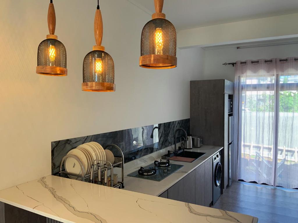 a kitchen with three lights hanging over a counter at Villa Oleemun Rezabeen - Mont Choisy in Mont Choisy