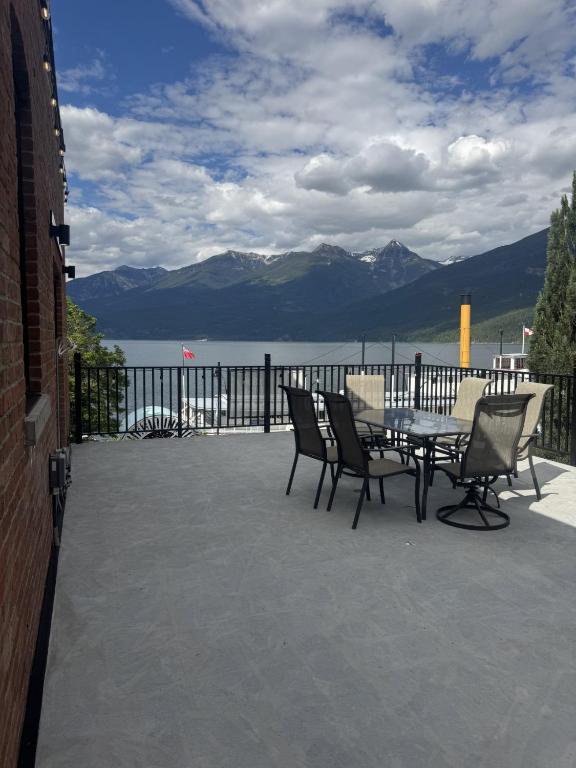 a patio with a table and chairs with a view of a lake at Lokis Loft and Cellar at the 1896 Building in Kaslo