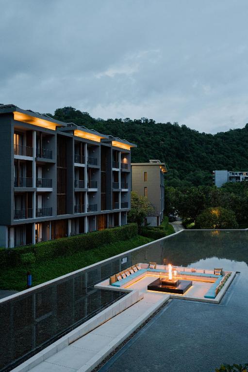 a building with a fire pit next to a swimming pool at The Peri Hotel Khao Yai in Phayayen
