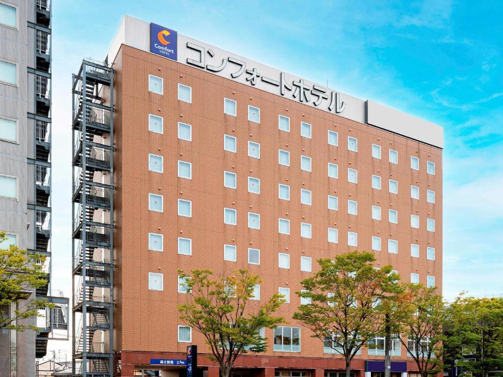 a building with a sign on the side of it at Comfort Hotel Tsubamesanjo in Sanjo