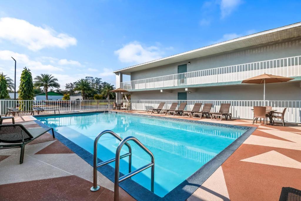 a pool at a hotel with chairs and umbrellas at Quality Inn near Blue Spring in Orange City