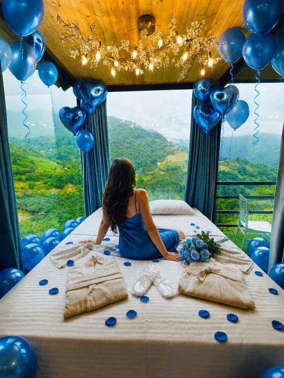 a woman sitting on a bed in a room with balloons at Sunrise house merisi in Merisi