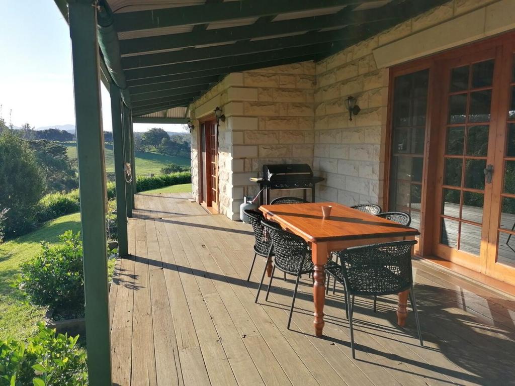 a wooden deck with a table and chairs and a piano at Hank's Folly in Wapengo