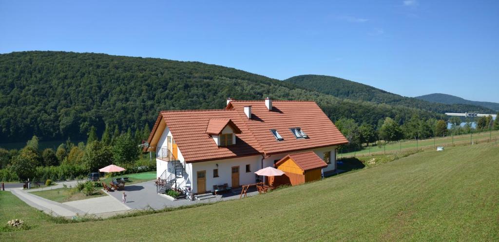een huis met een rood dak bovenop een heuvel bij Noclegi "Koniadów" in Solina