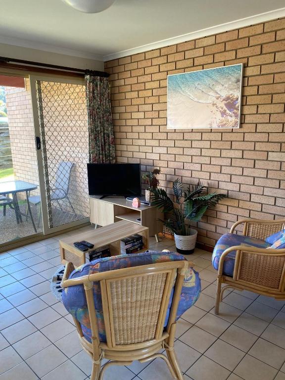 a living room with two chairs and a table and a television at Edna's Retreat in Tathra