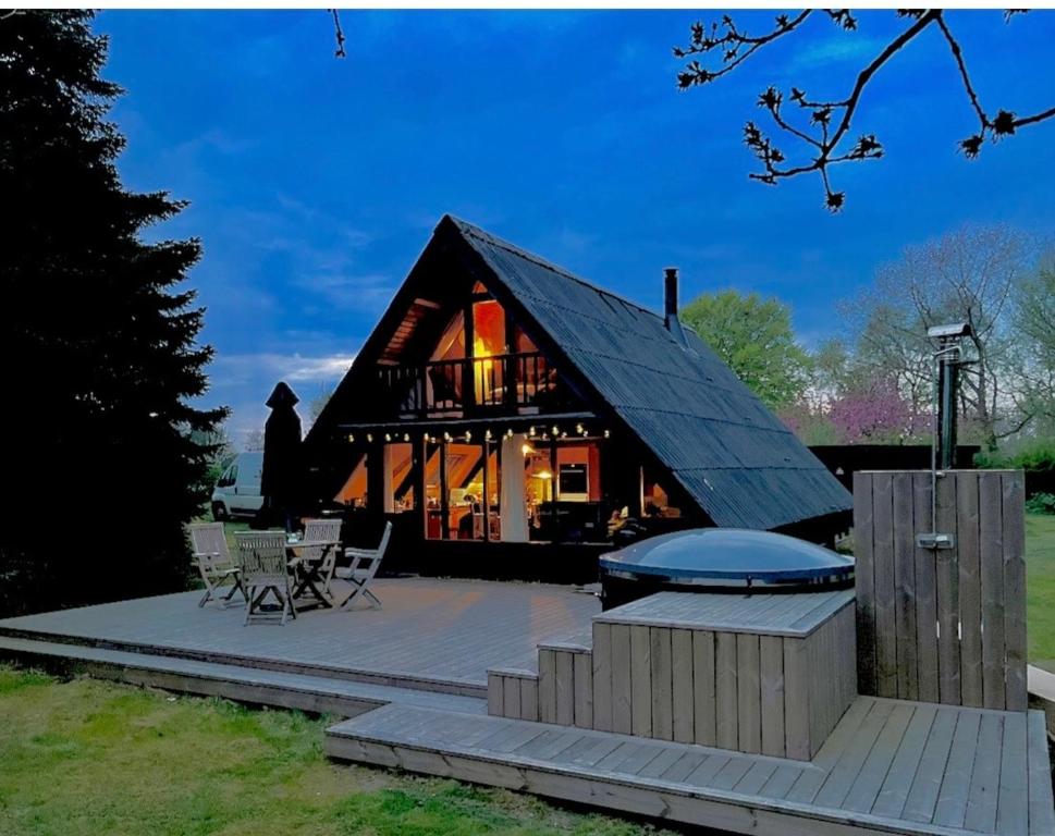 a log home with a deck and a fire pit at Authentic wooden summer house in Øster Hurup