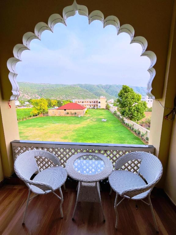 a table and chairs on a balcony with a large window at Horizon Resort Pushkar-Feel of The Nature in Pushkar