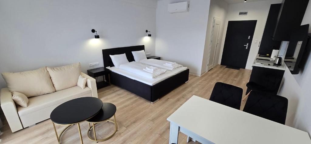 a living room with a bed and a couch at White Pearls Apartaments Dąbki in Dąbki