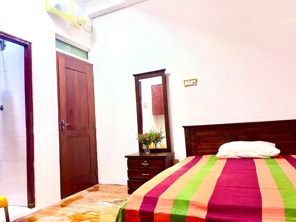 a bedroom with a colorful bed and a mirror at Studio Greenlands 2nd-E in Battaramulla